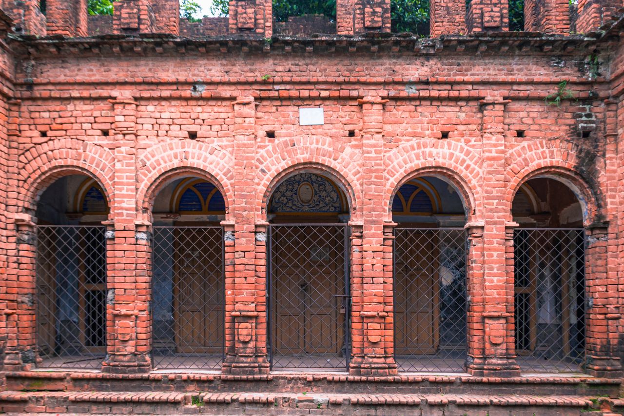 A historic building facade with red brick arches and iron grills, showcasing classic design.