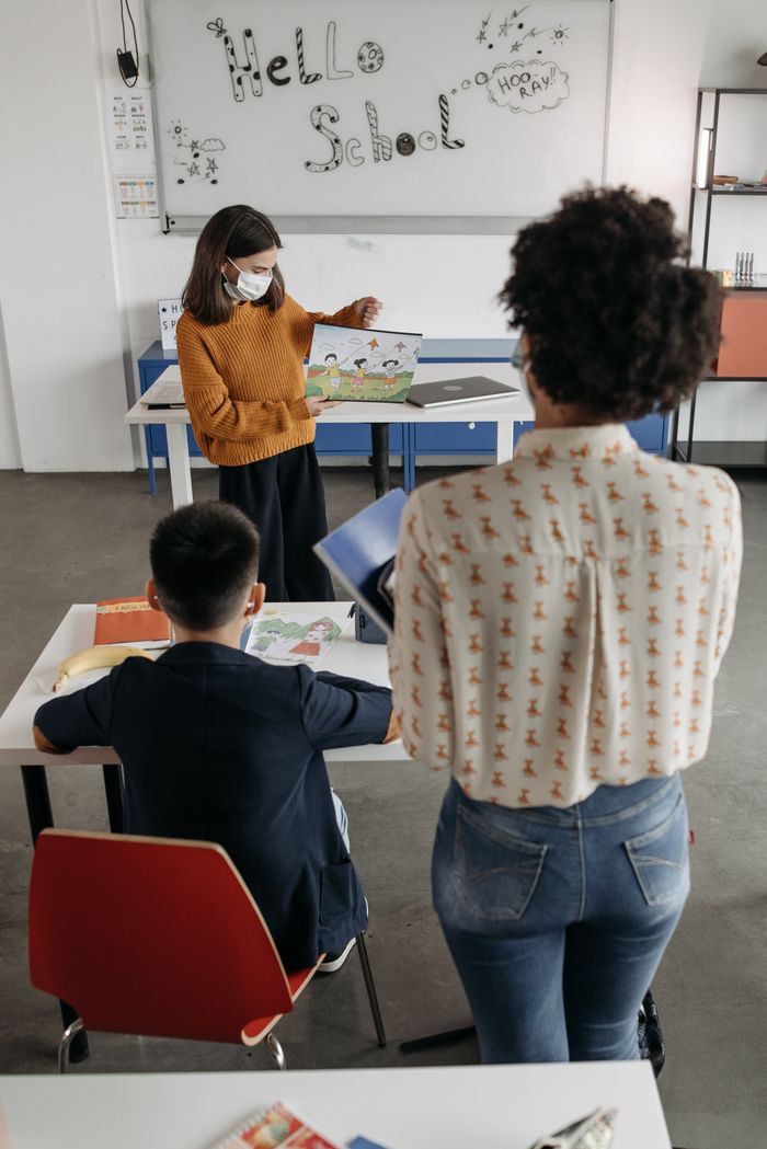 Teacher instructing students in classroom setting during pandemic, showcasing diverse learning.